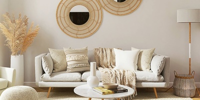 Wohnraum mit Couch, Wandspiegeln, Couchtisch, Teppich und Lampe
